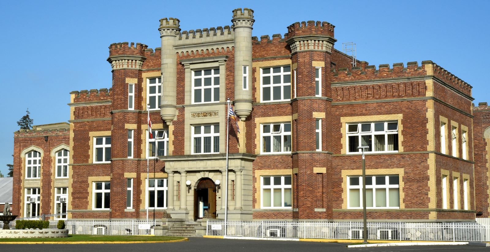 A three-storey institutional building of brown brick with castle-like turrets.