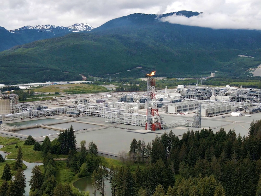 A sprawling industrial project, with a flaring tower at the centre, sits amidst a mountain landscape.
