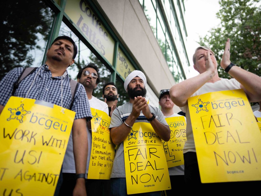 A group of people stand outside, with yellow signs.