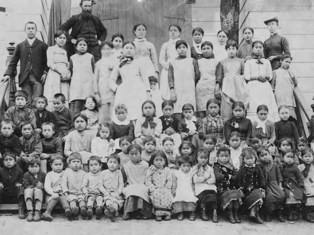 A black and white school photo of residential school staff and students.