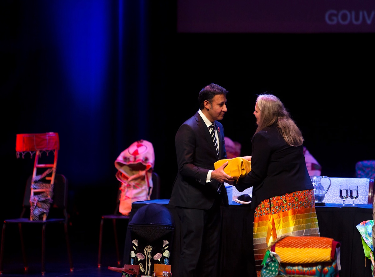 Kimberly Murray and Arif Virani meet onstage, exchanging a package wrapped in cloth.