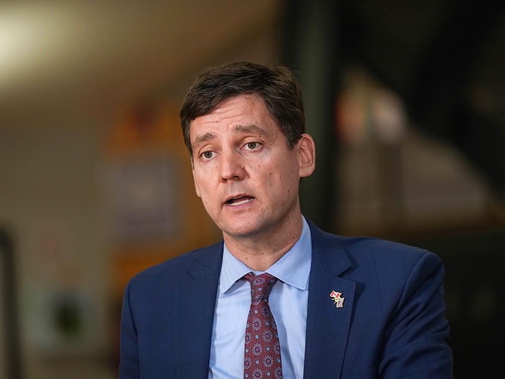 David Eby, a 48-year-old light-skinned man, wears a blue suit and is in mid-speech.