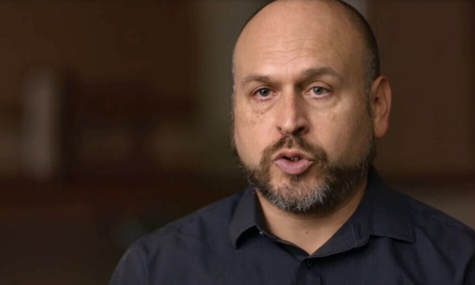 Gil Duran, a man with light skin, close-cropped thinning hair and salt-and-pepper beard, in mid-speech.