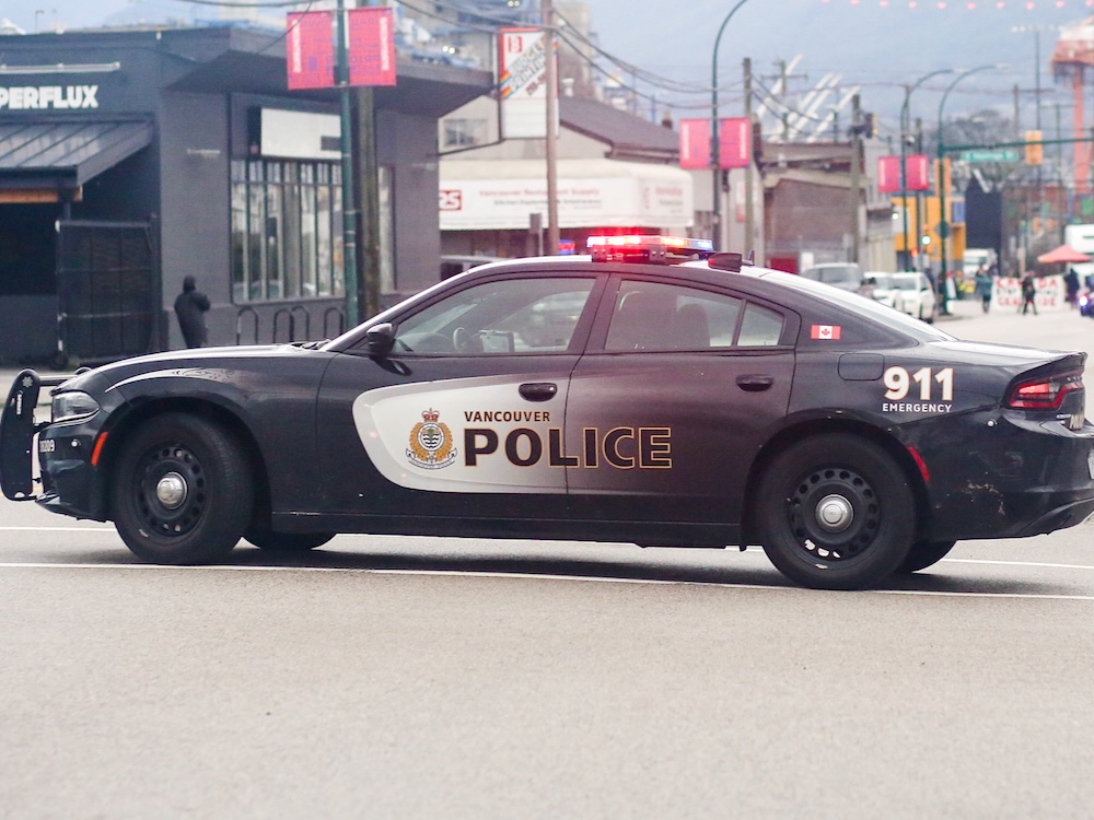 A Vancouver police car with its lights on on a downtown street.