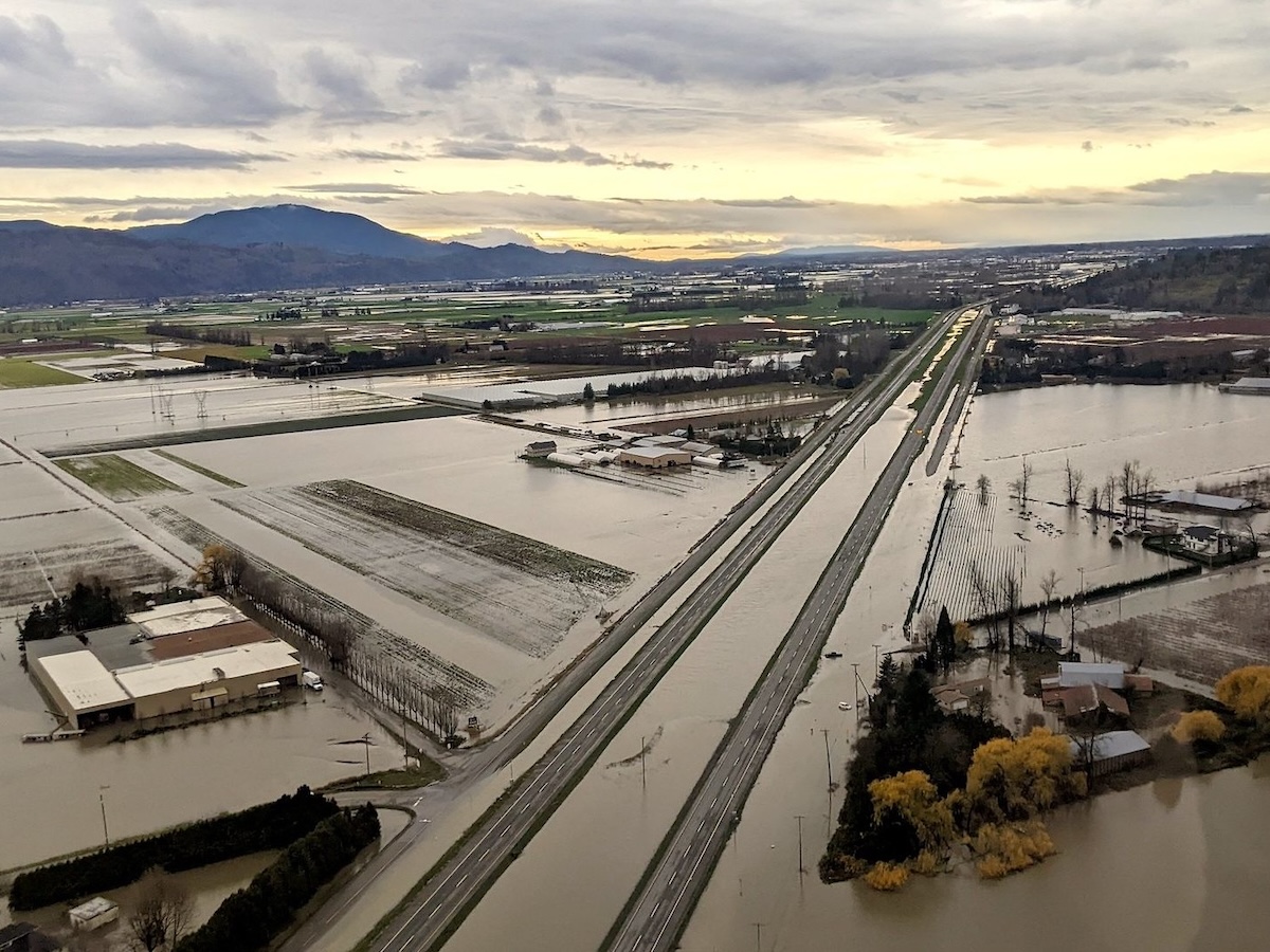 From a traffic camera: the highway and the fields alongside it are completely flooded. A traffic display reads, &lsquo;Very slow traffic. Reduced speed ahead.&rsquo;