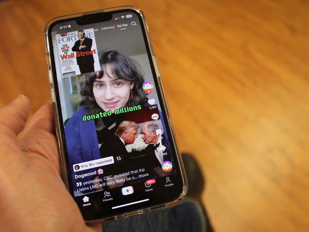 A hand is holding a cellphone displaying political content.
