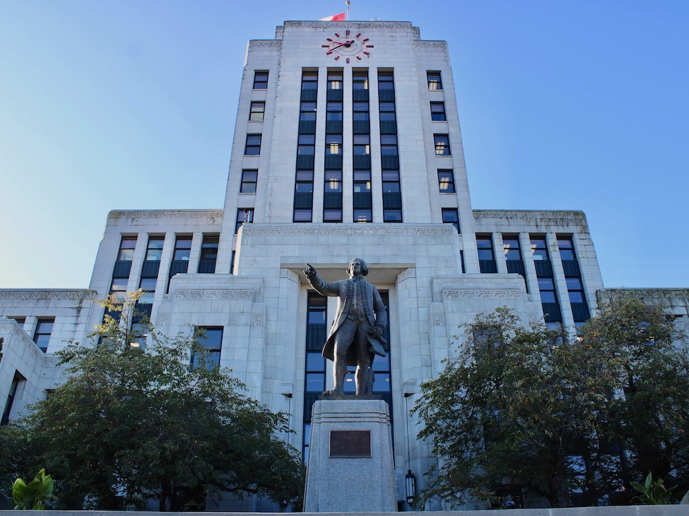 A grey cement art deco building, Vancouver City Hall, on a sunny day in fall.