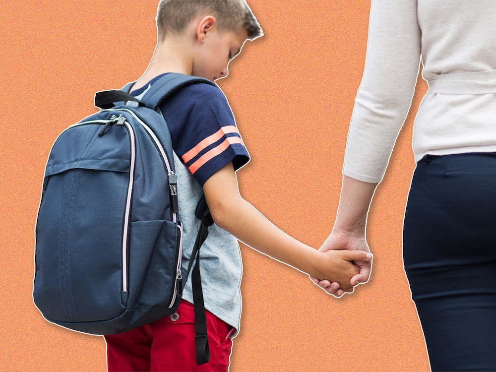 A young boy wearing a backpack holds his mom&rsquo;s hand. He looks sad.