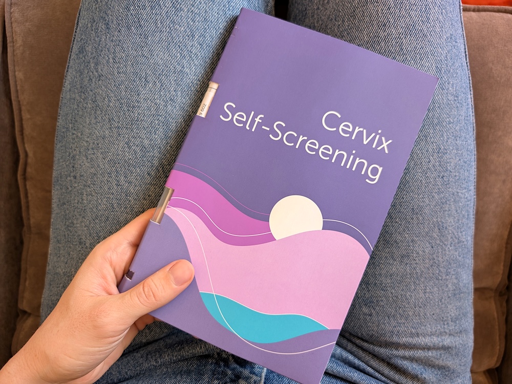 A person holds a cervical cancer screening kit in their lap.