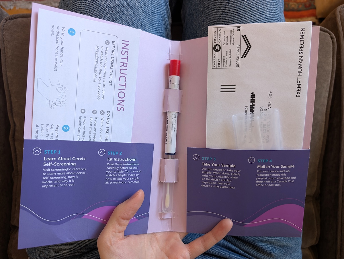 A person holds an open cervical cancer screening kit in their lap. 