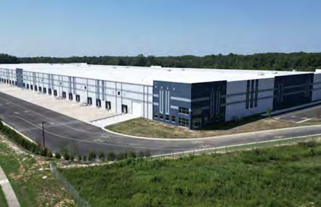 A very large warehouse building is surrounded by parking lots.