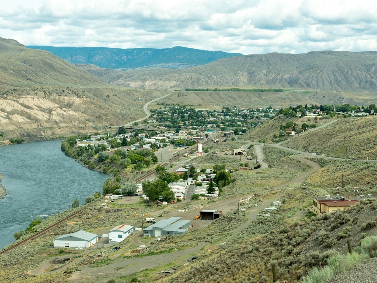 A community sits at the bottom of a rugged, arid valley, next to a river.