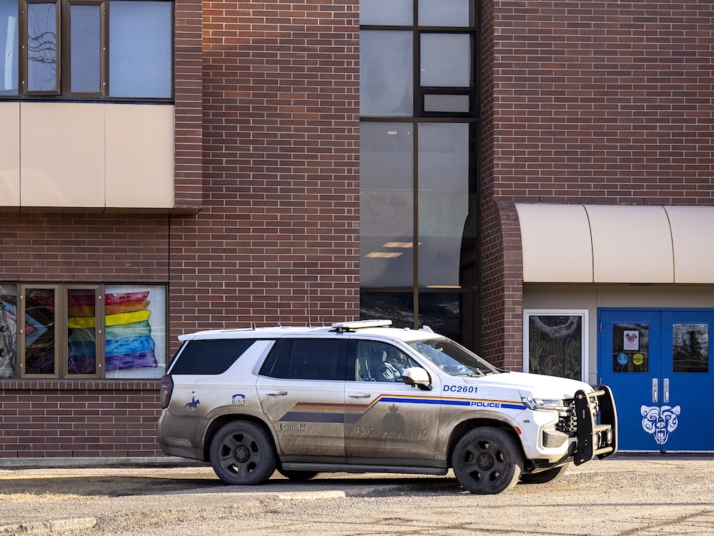 An RCMP cruiser is in front of school, where windows have a painted Pride symbol.