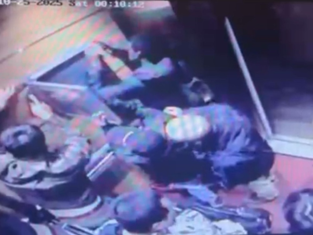 A group of men dismantles a flat object on a wall in an elevator.