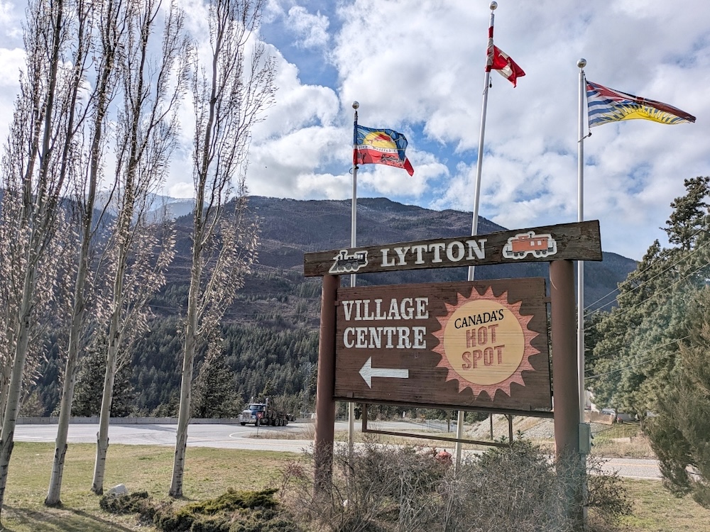 A wooden sign reads &lsquo;Lytton. Village Centre&rsquo; with an arrow and Lytton&rsquo;s motto: &lsquo;Canada&rsquo;s hot spot.&rsquo;