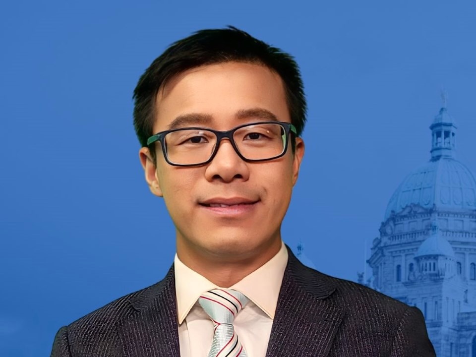 A 40-ish man of medium-light skin tone wears a suit and looks at the camera.