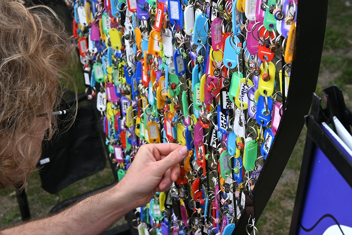 People attach key tags with the names of lost loved ones to a metal heart.