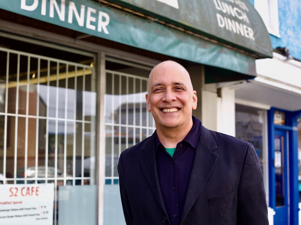 A middle-aged man smiles at the camera. He wears a dark sports coat and button-down shirt with no tie.