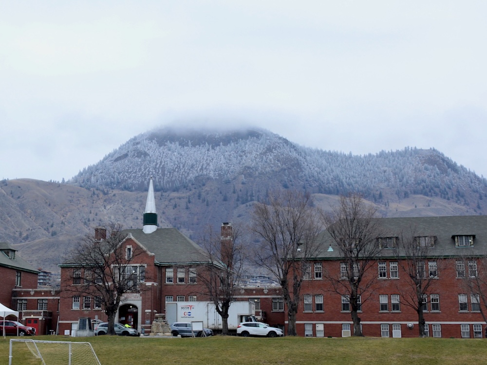 A red brick building in front of snow-capped mountains.