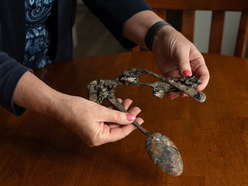 A woman's hands hold a pair of charred spoons melted together.