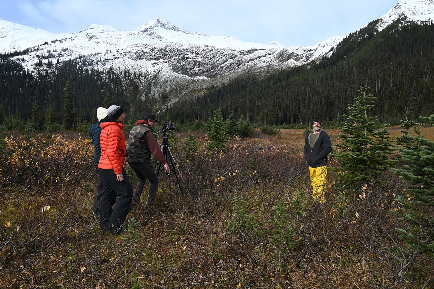 Four people stand in the Raush valley, preparing to film.