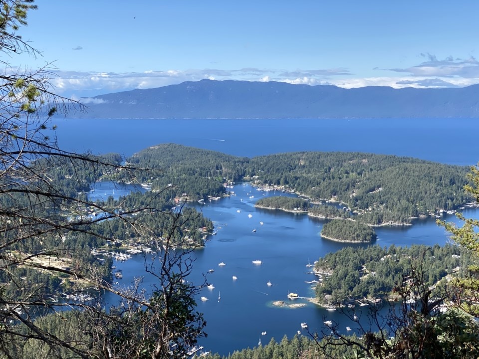 A photo showing the ocean, mountainous islands and small white boats. The view is taken from an elevated point.