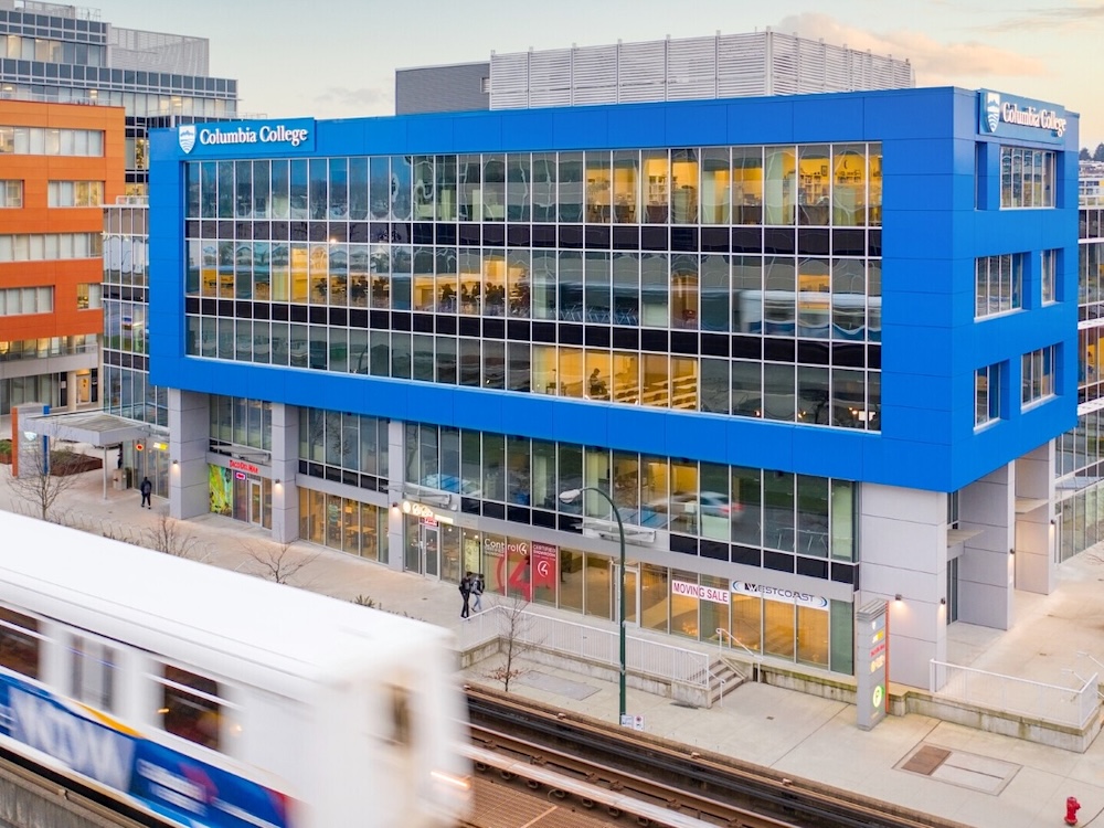 A five-storey office building with a blue facade on the top floors and signs that say &lsquo;Columbia College.&rsquo;