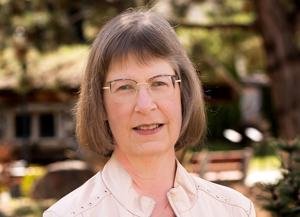 A light-skinned woman with chin-length hair and glasses.