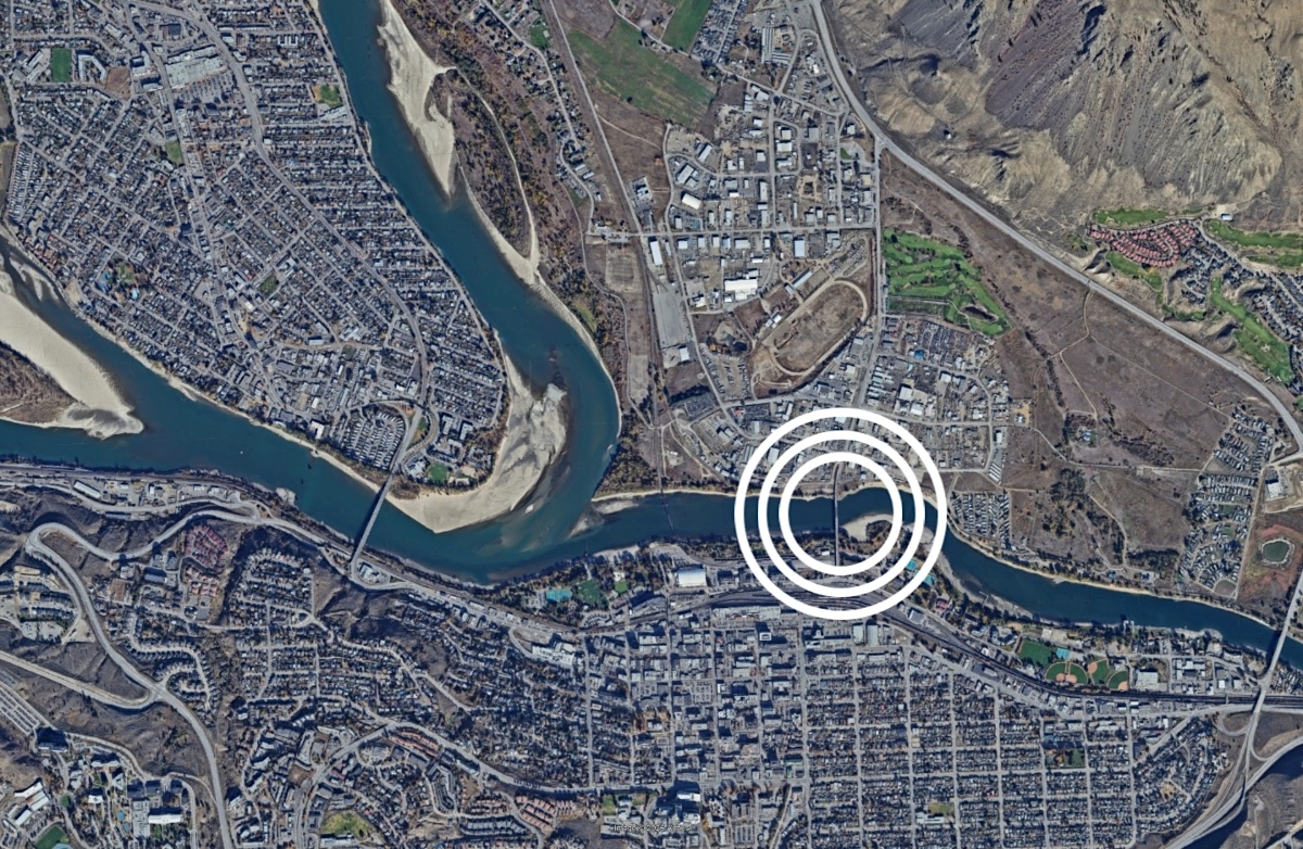 A satellite image of a city at the confluence of two rivers. A bridge over one of the rivers is circled.