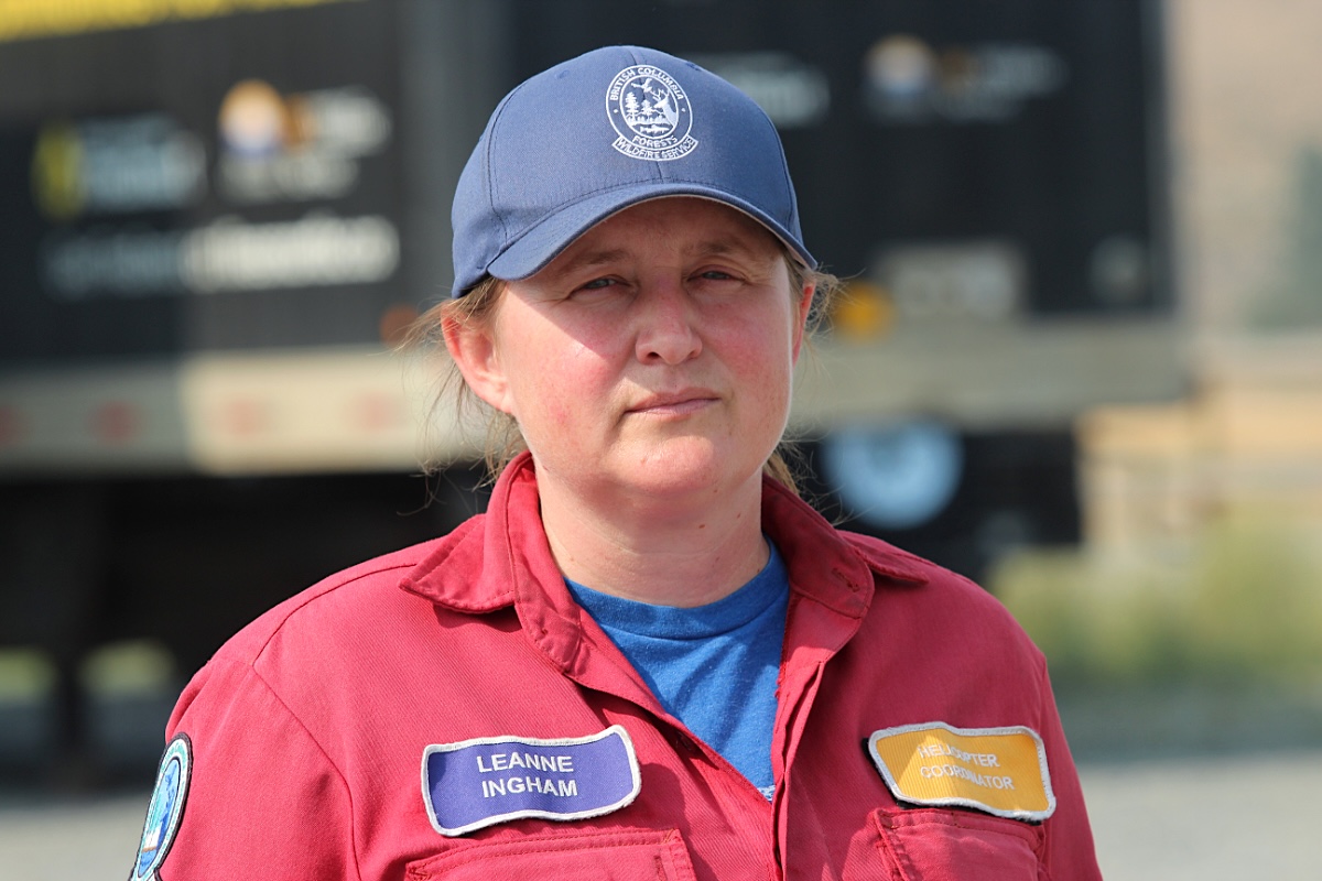 Leanne Ingham is wearing a blue hat and a red firefighting uniform over a blue shirt.
