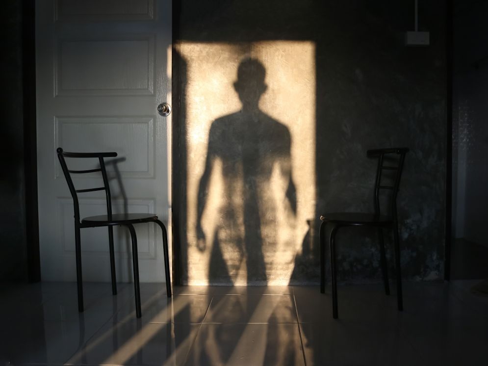 A shadow of a man is cast on a wall in a room.