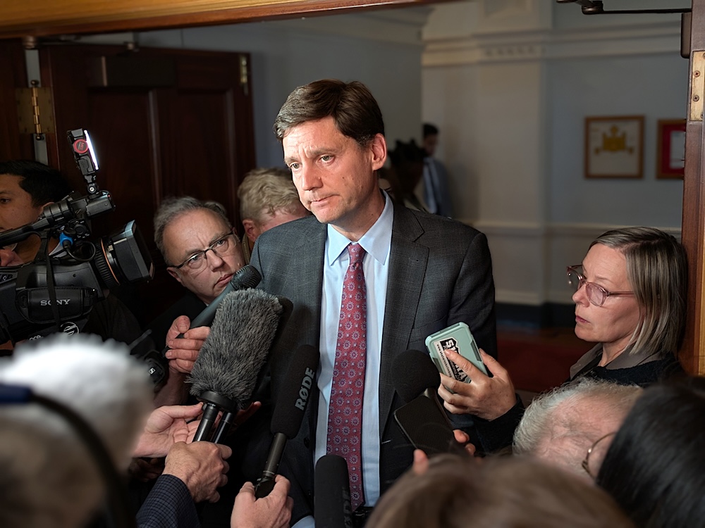 David Eby is in the provincial legislature, surrounded by microphones and journalists.