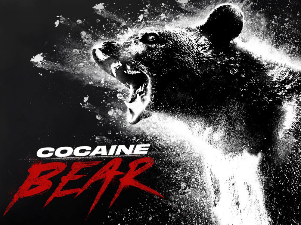 A black and white image shows a crazed looking bear and masses of white powder. The words &lsquo;Cocaine Bear&rsquo; are superimposed.