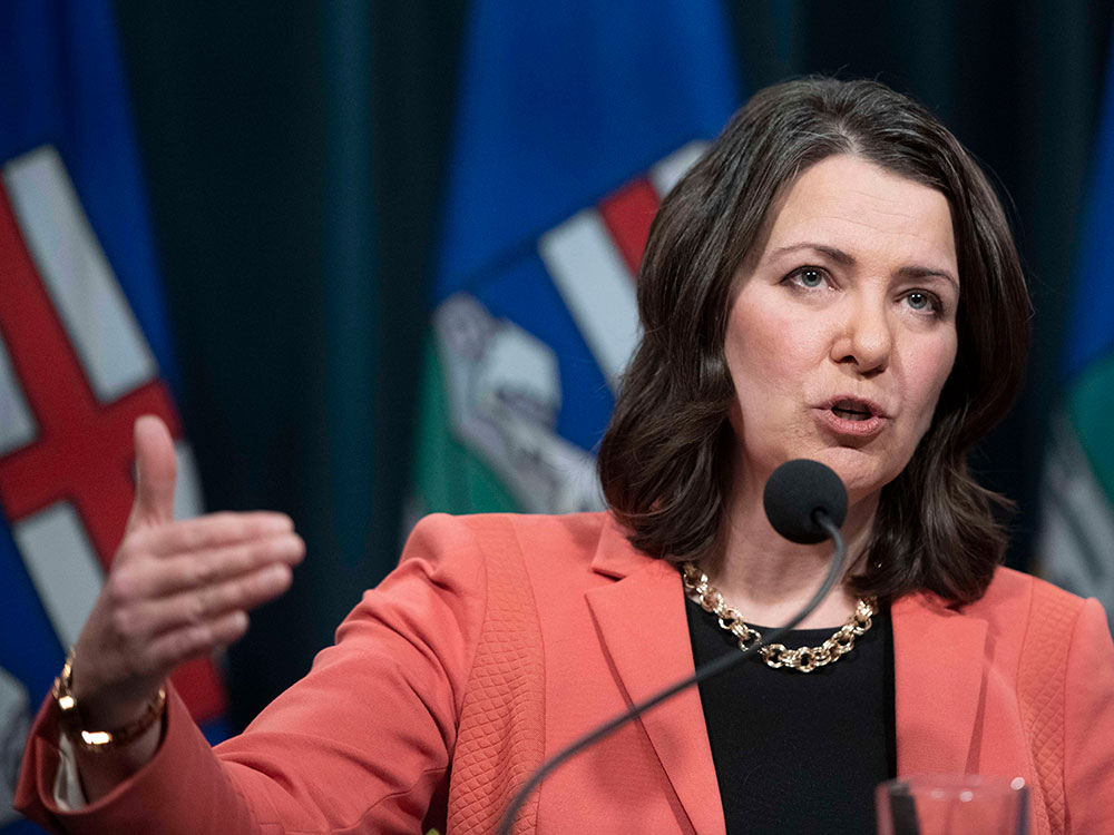 UCP Leader Danielle Smith gestures as she speaks behind a podium.