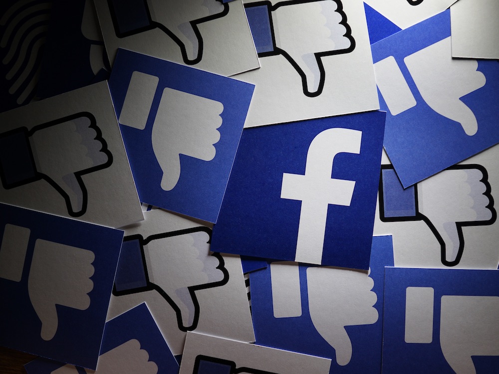 A graphic of the Facebook logo with the thumbs down icon in the background.