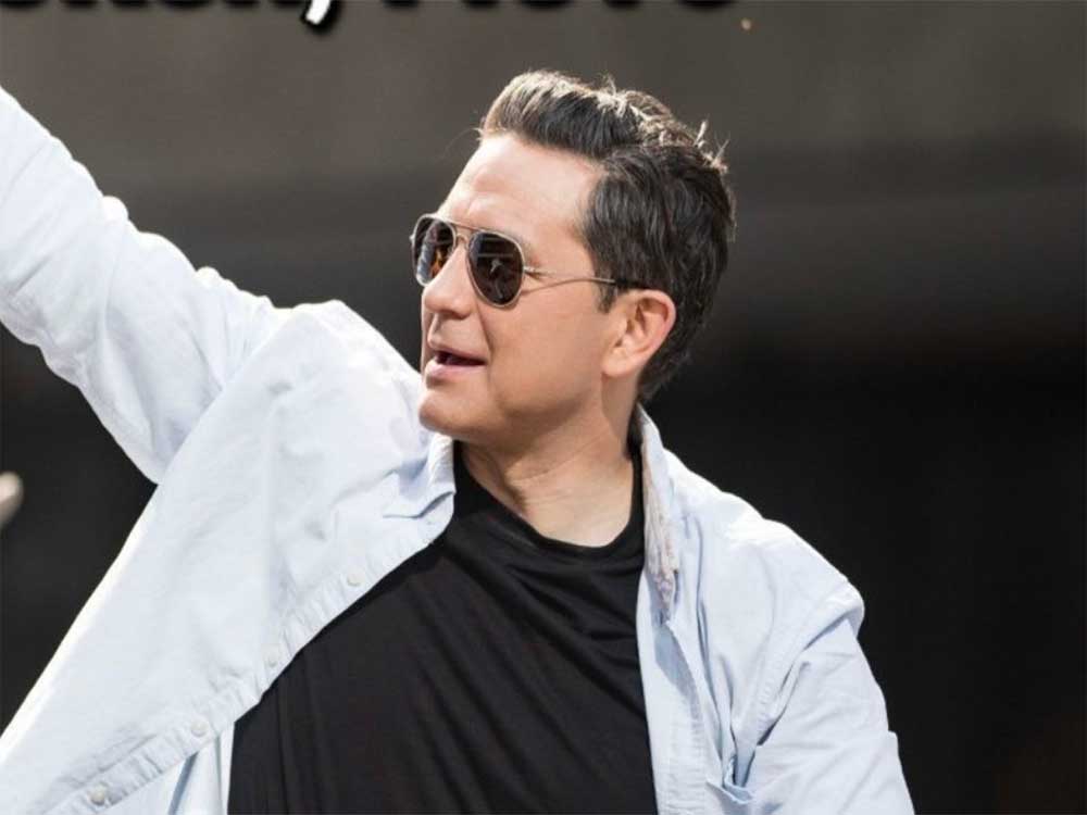 Pierre Poilievre sports aviators, a black tee and white jacket. 