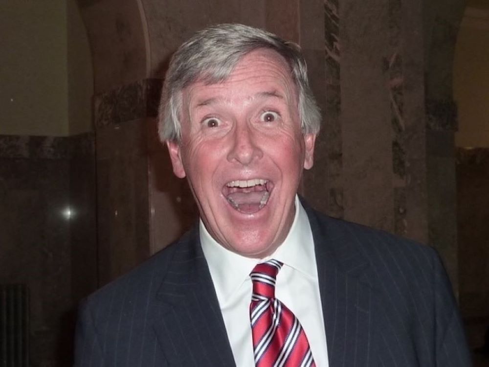 Jim Dinning, in a suit, smiles wildly at the camera.