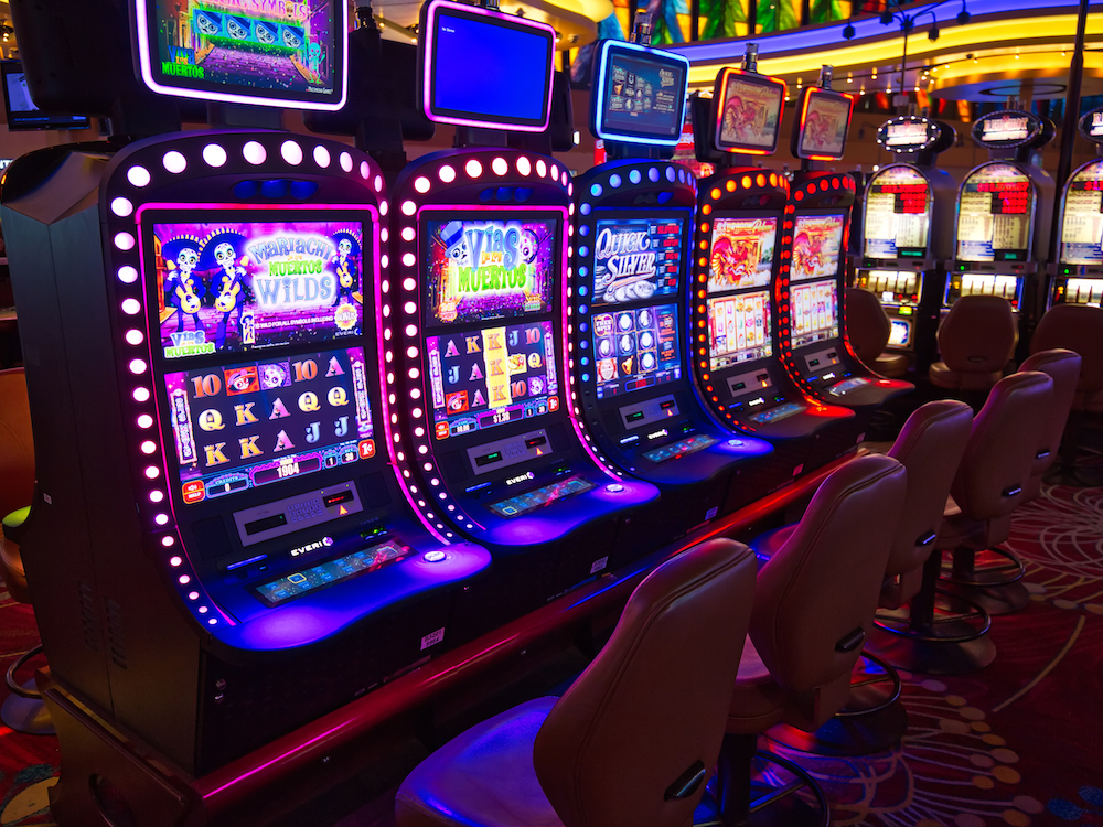 Rows of slot machines glow in a gambling hall.