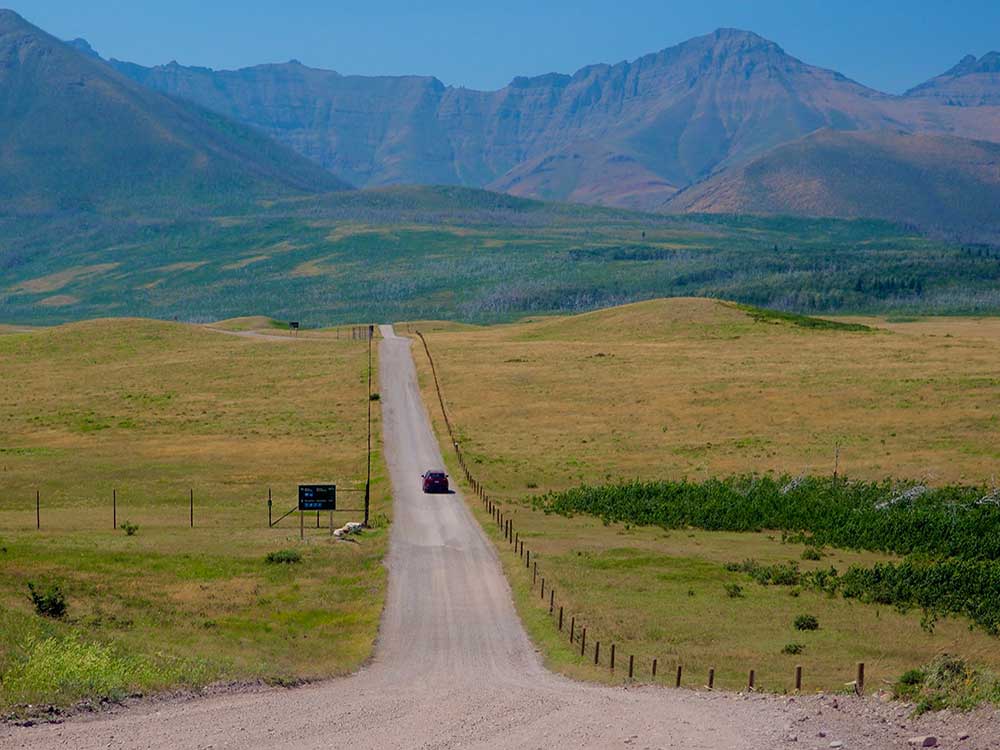 A gravel road stretches toward a mountain range.