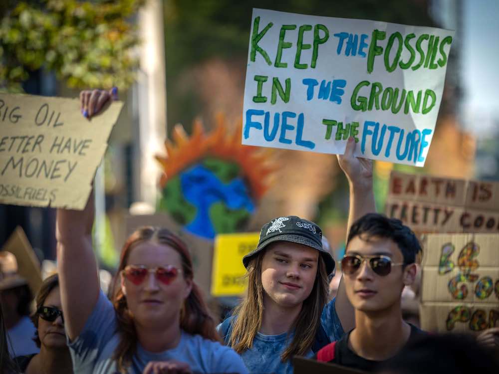 Three people are part of a protest holding signs.