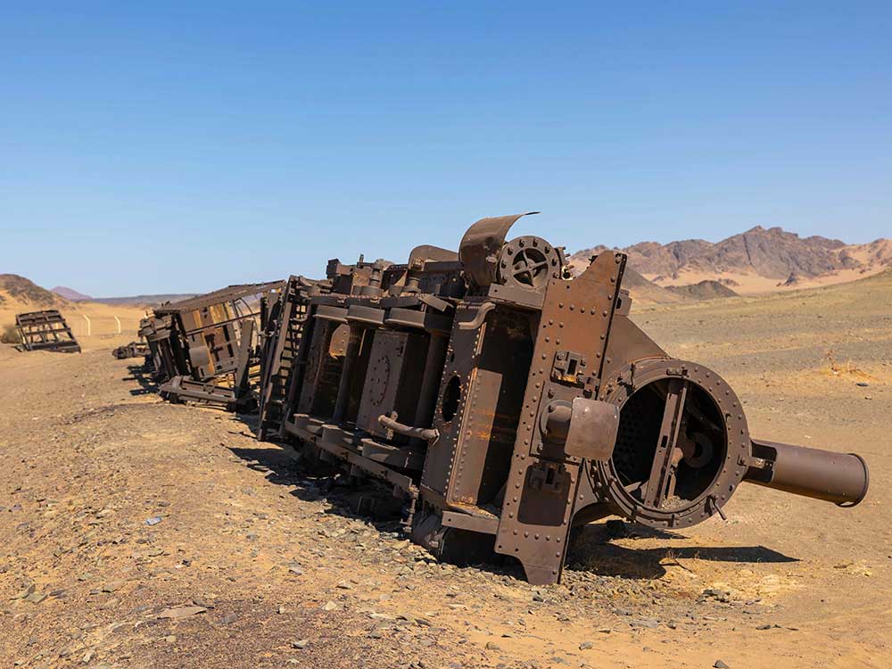 Rusted, wrecked train cars lay in the desert.