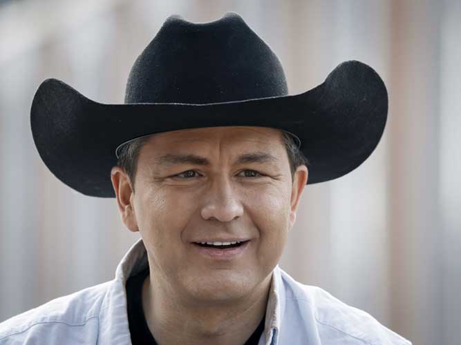 A medium close-up of Pierre Poilievre smiling and wearing a cowboy hat. 