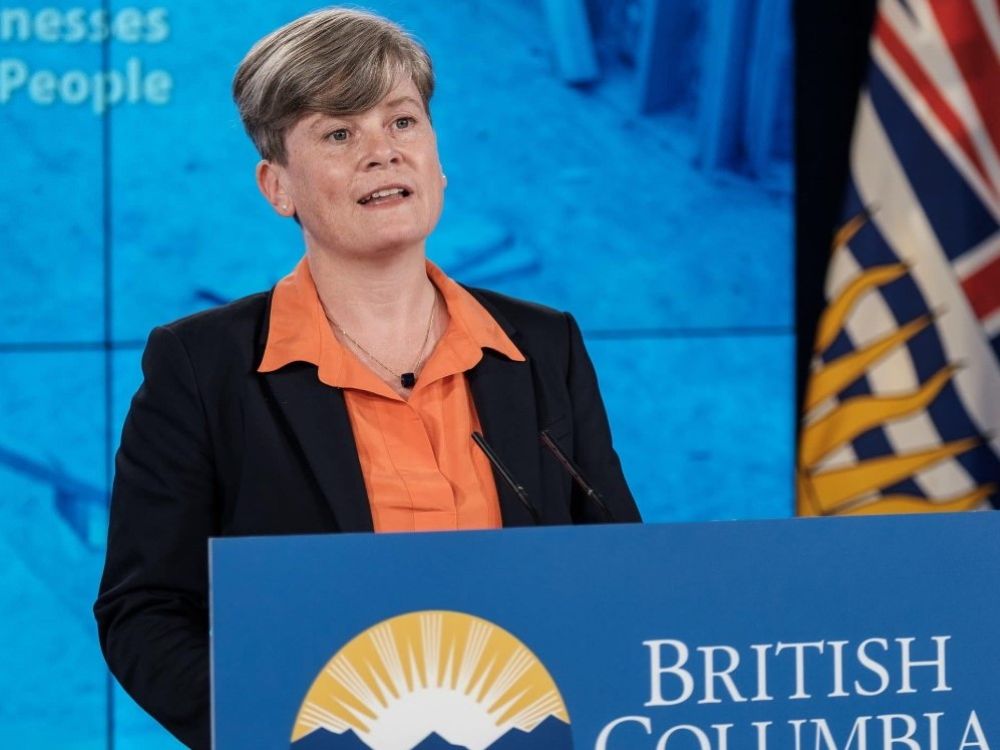 Health Minister Josie Osborne, A light-skinned woman with short hair stands at a podium.