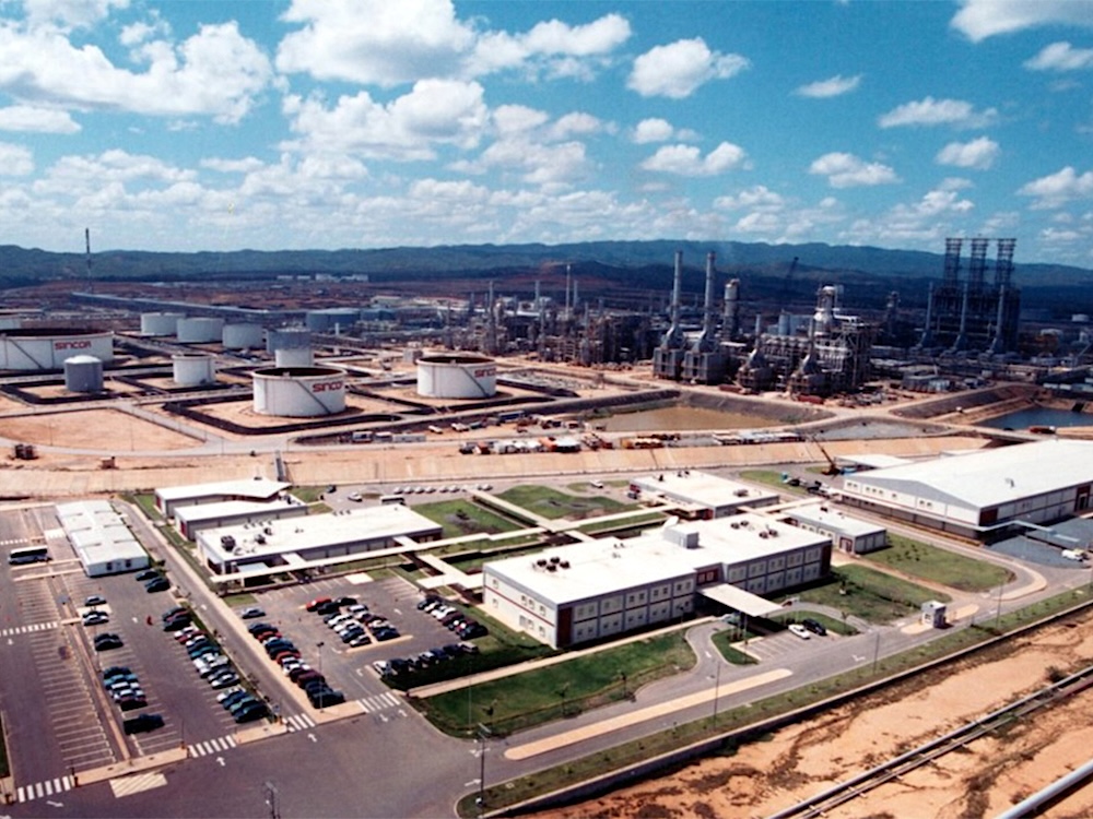 An aerial photo shows a large oil production facility, with tanks, large buildings and processing facilities.