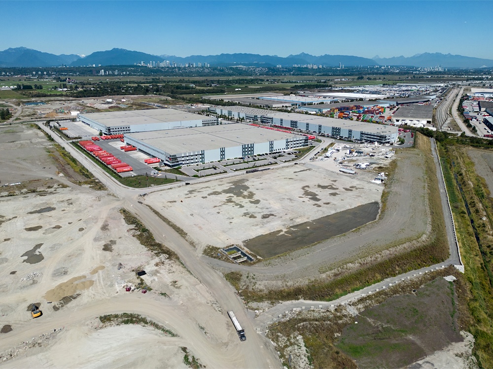 An aerial shot of a flat portion of Richmond that is home to several industrial parks. Mountains are visible in the distance.