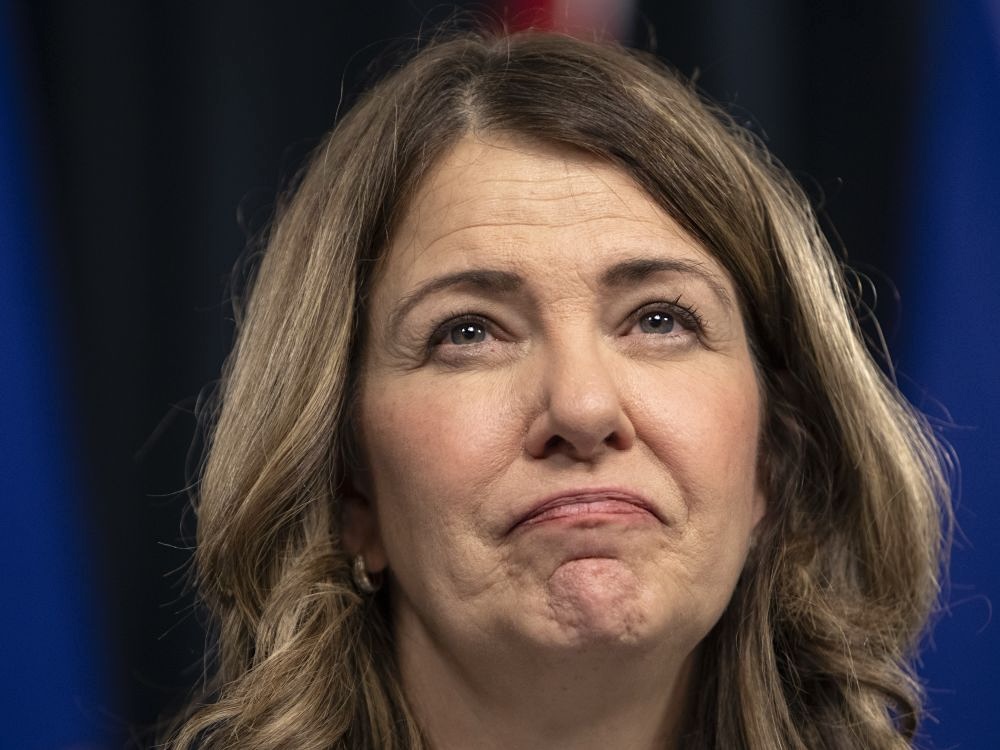 Danielle Smith, a 60-ish light-skinned woman with wavy brown hair, frowns.