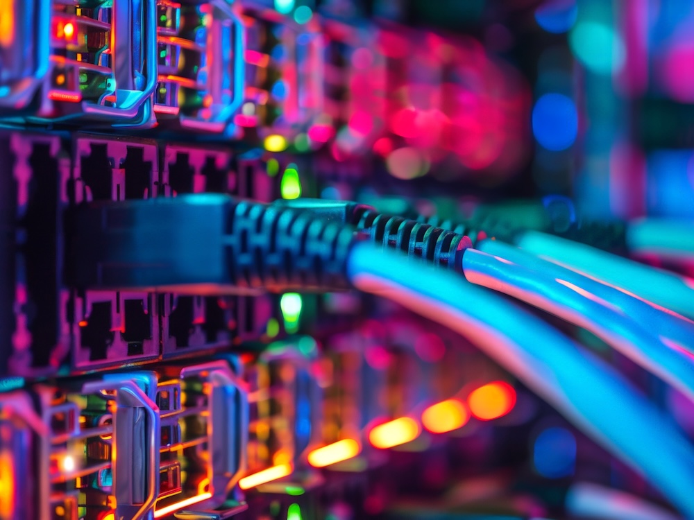 Brightly coloured lights illuminate several computer cables connecting to a server.