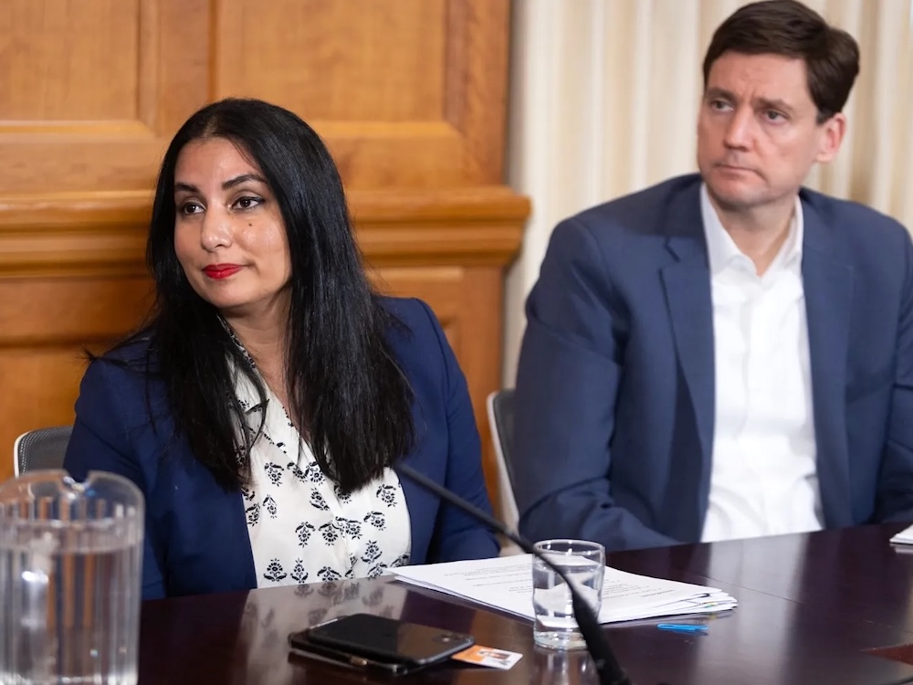 Niki Sharma, a woman with medium-toned skin and long dark hair, sits beside Premier David Eby, a light-skinned man.