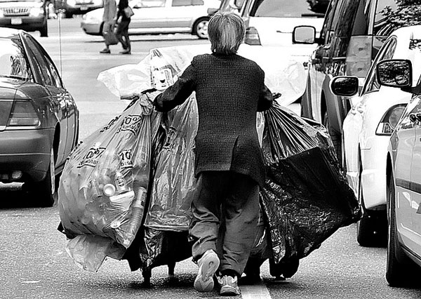 Man pushing cart with bottles and cans