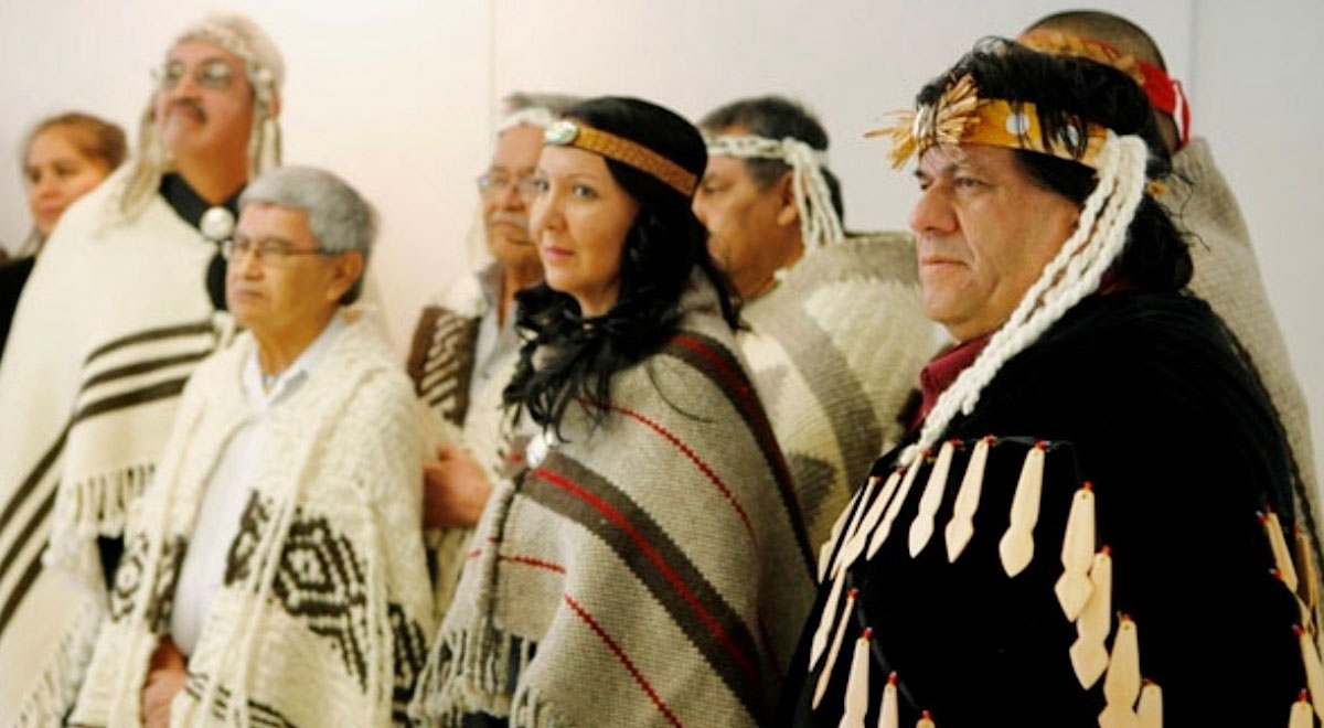 A younger Lydia Hwitsum stands among a group of Chiefs of the Hul&rsquo;qumi&rsquo;num Treaty Group, dressed in regalia.